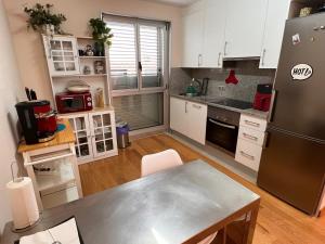 a kitchen with white cabinets and a stainless steel refrigerator at Loft con PARKING "Hygge Urbano Coruña" in A Coruña