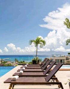 een rij ligstoelen naast een zwembad bij Luxury Studios On The 5th avenue Ocean View Rooftop I By Yeah in Playa del Carmen