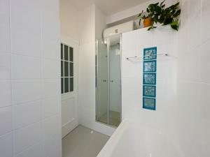 uma casa de banho branca com um chuveiro e uma porta de vidro em Litta's flat in Affori - 3 mins walk from MM3 em Milão