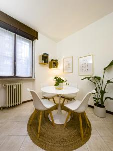 uma sala de jantar com uma mesa branca e cadeiras em Litta's flat in Affori - 3 mins walk from MM3 em Milão