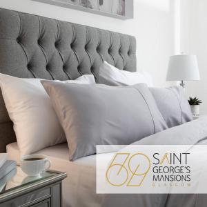 uma cama com almofadas brancas e uma placa que diz sant groves em 69 St Georges Mansions em Glasgow