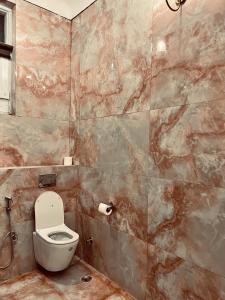 a bathroom with a toilet and a tiled wall at Mundota Fort And Palace in Pachār