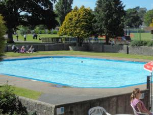 a swimming pool in a park with people sitting around it at Riverside Mews in Bideford