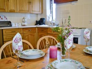a dining room table with plates and glasses and flowers at Greenmeadow Bungalow in Llanon