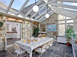 a conservatory with a table and chairs and a stone wall at Lower Margate Bodmin in Bodmin