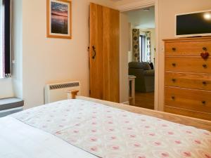 a bedroom with a bed with a dresser and a television at The Bothy in Bradworthy