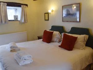 特勞特貝克的住宿－Granary Cottage，卧室配有白色床和毛巾