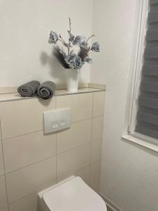 a bathroom with a toilet and a vase with flowers at Tolle Ferienwohnung im Herzen von Thüringen in Eisenach