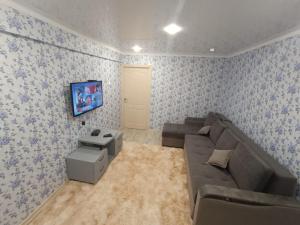 a living room with a couch and a tv at Lux Home на Амурской in Ustʼ-Kamenogorsk