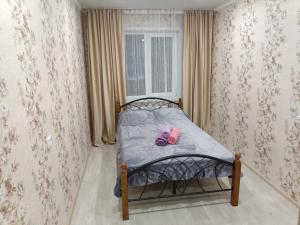 a small bed with a pair of pink shoes on it at Lux Home на Амурской in Ustʼ-Kamenogorsk