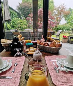 a table with a breakfast of bread and orange juice at Entre monts et collines B&B et espace détente in Mont-de-l'Enclus