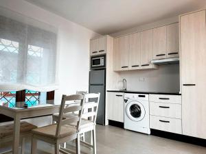 cocina con armarios blancos, mesa y sillas en Apartamentos Turísticos Magallanes I en San Pedro del Pinatar