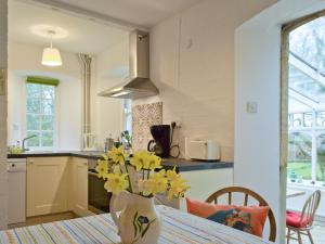 een keuken met een tafel met een vaas met gele bloemen bij Jubliee Cottage in Enstone