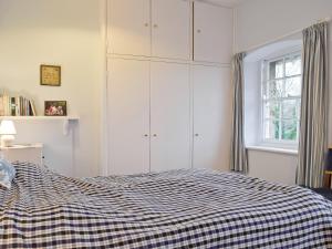 a bedroom with a bed with a checkered blanket at Jubilee Cottage in Enstone