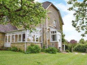 een oud bakstenen huis met een grote serre bij Jubliee Cottage in Enstone