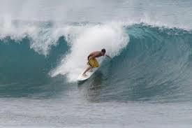 un hombre montando una ola en una tabla de surf en el océano en Résidence Fanti, en Sidi Binnzarene