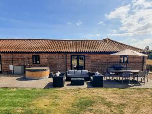 a brick house with a patio with a couch and a table at Summer House Stables in Catfield
