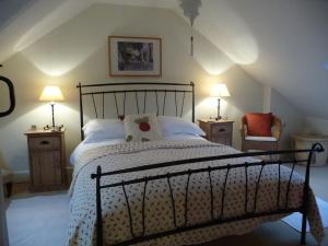 a bedroom with a bed and two lamps and a chair at Brook Cottage in Baltonsborough