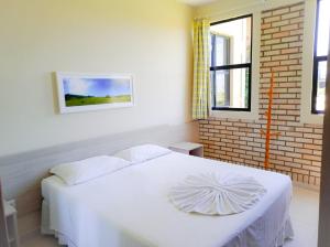 Cama blanca en habitación con pared de ladrillo en Silvestre Praia Hotel, en Imbituba