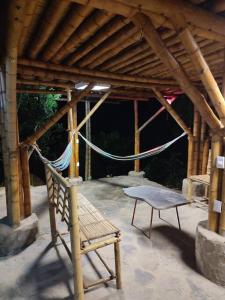 una hamaca y una silla bajo un pabellón de madera en Colibamboo The Cabin. Cabaña elevada con mirador montaña malla y jacuzzi, en Pacho