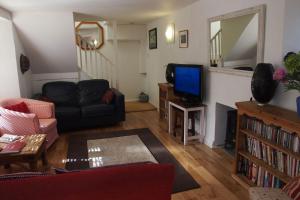 a living room with a couch and a television at Priory Cottage in Totnes