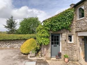 an ivy covered stone house with a door at Tophams Laithe in Kilnsey