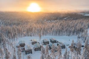 un groupe de lodges dans la neige avec le coucher du soleil en arrière-plan dans l'établissement Levillas Levin Tuulahdus, à Sirkka