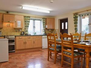 a kitchen with a wooden table and chairs and a table and a kitchen with at Swallow Cottage in Llanfair Caereinion