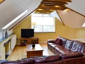 a living room with a leather couch and a tv at White Dove Barn in Wembury