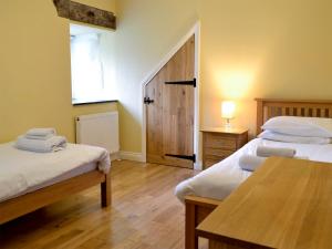 a room with two beds and a table and a window at White Dove Barn in Wembury