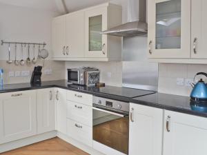 a kitchen with white cabinets and a stove top oven at Haulfryn Cottage in Menai Bridge