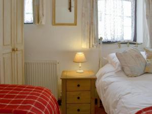 a bedroom with a bed and a lamp on a night stand at Cross Cottage in Saint Breward