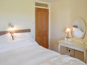 a bedroom with a white bed and a mirror at Castle House Cottage in Horton