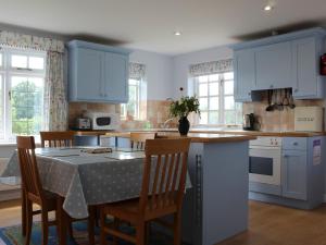 een keuken met blauwe kasten en een tafel met stoelen bij Castle House Cottage in Horton