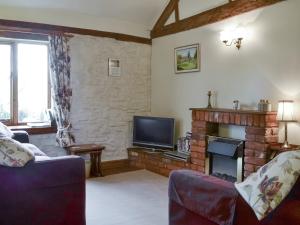 a living room with a fireplace and a tv at The Coach House in Kington