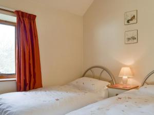 two beds in a room with a window at The Coach House in Kington