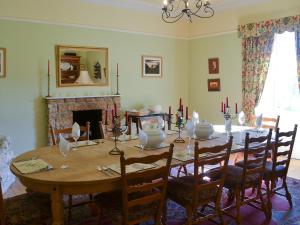 a dining room with a table and a fireplace at Byrness House in Byrness