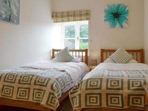 two beds sitting next to each other in a bedroom at Sgubor Ucha in Trefriw