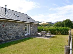 a patio with a table and chairs and an umbrella at Sgubor Ucha in Trefriw