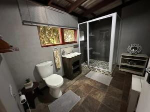y baño con aseo, lavabo y ducha. en BayView Room @ Coram Deo, en Coffee Bay