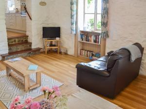 a living room with a leather couch and a table at Babes Cottage - 27592 in Perranzabuloe