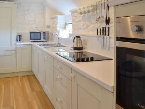 a white kitchen with a sink and a stove at Babes Cottage - 27592 in Perranzabuloe