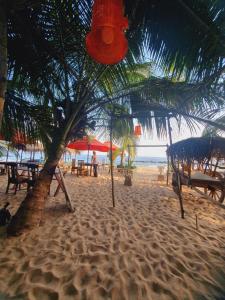 a beach with tables and chairs and a palm tree at Blue Horizon Beach Hotel in Tangalle