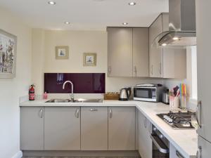 a kitchen with white cabinets and a sink and a microwave at Abacus in Two Dales