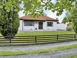 a white house with a fence in front of it at Foresters Cottage in Kildary