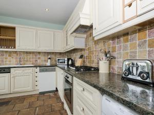 a kitchen with white cabinets and a counter top at Harbour Cottage in Port William