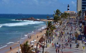 a crowd of people on a beach with a lighthouse at Farol Barra Flat completo e bem localizado in Salvador +9 photos