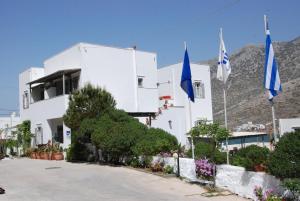 un bâtiment blanc avec deux drapeaux devant lui dans l'établissement Myrto Hotel, à Kamarai