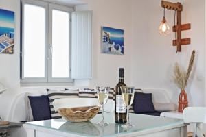 una sala de estar con una mesa con botellas de vino y copas en Antheia Suite of Mykonos, en Ano Mera