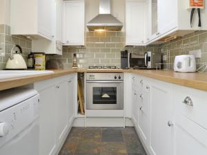 a kitchen with white cabinets and an oven at Pebble Cottage in Holt
